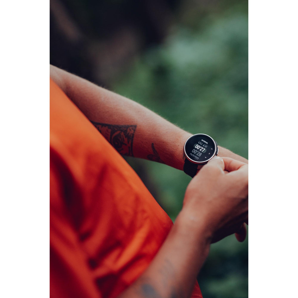 A runner adjusting the Suunto Race Titanium Charcoal smart watch on their wrist