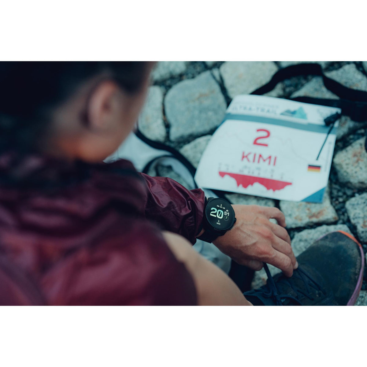 A runner looking at the Suunto Race All Black digital silicone smart watch on their wrist