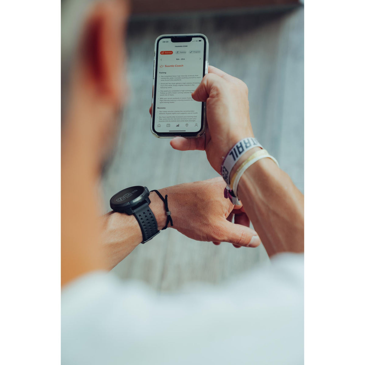 A person viewing fitness metrics on a smartphone application synced to their Suunto Race All Black watch