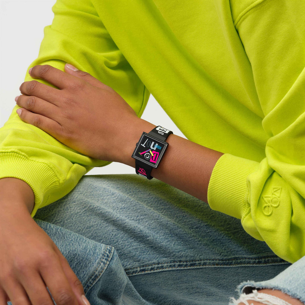 Black silicone strap watch with black dial and colorful abstract hands, worn on wrist