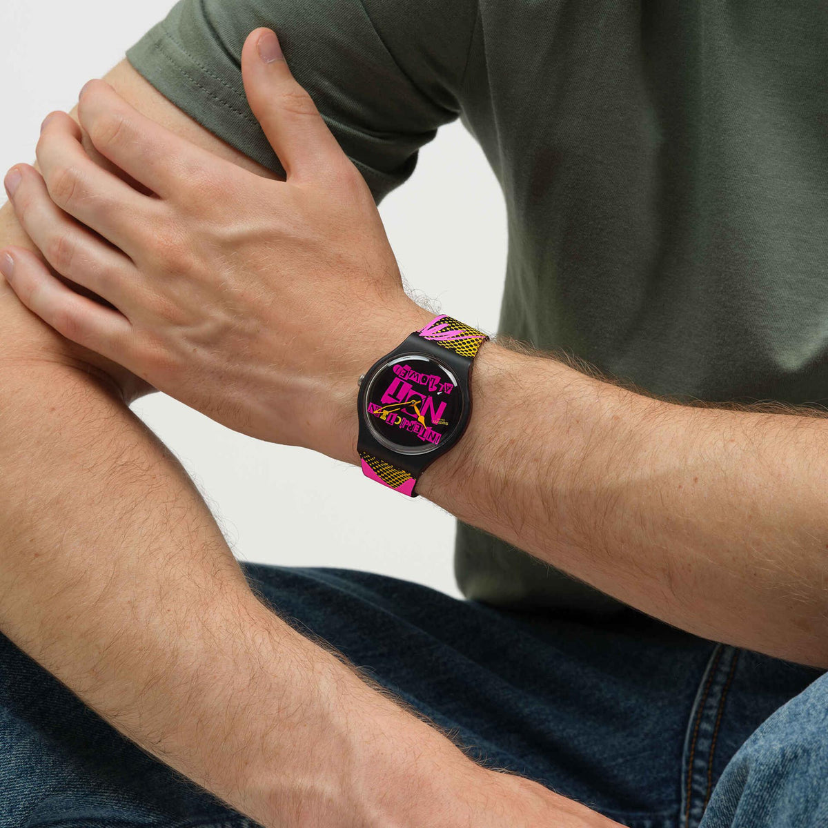 Silicone watch on wrist with black dial and neon pink/yellow geometric strap on forearm