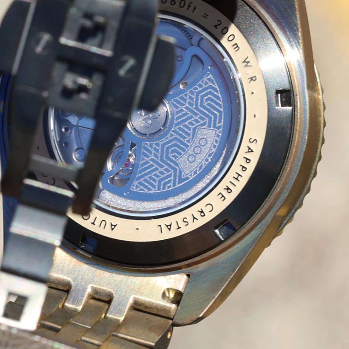 Close-up of watch caseback with blue geometric insert and engraved outer ring