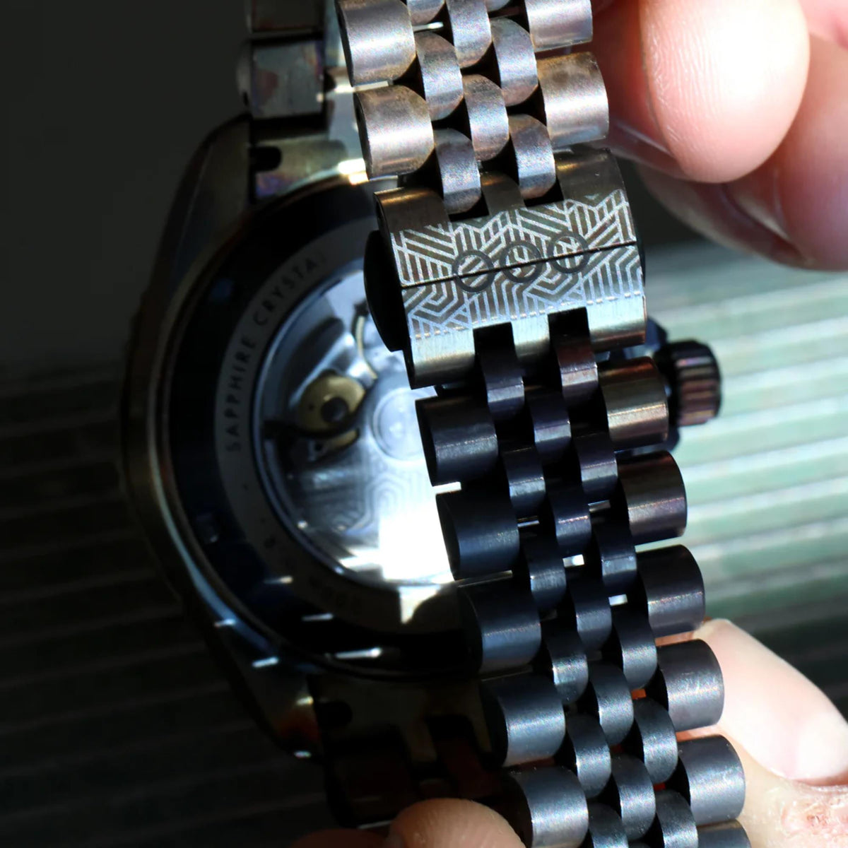 Macro view of metal link strap and watch caseback with textured detail