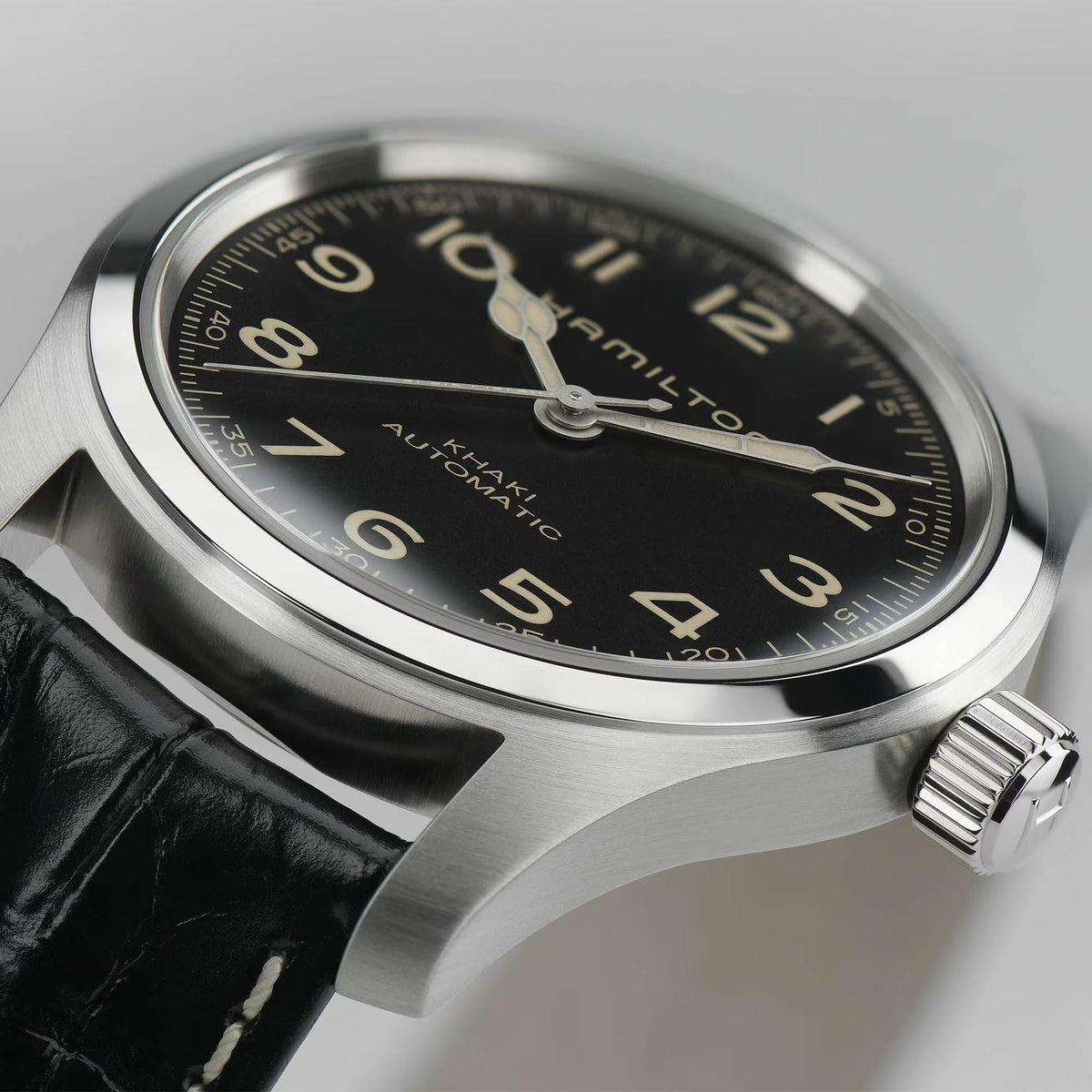 Macro detail of Hamilton Khaki Field Murph H70605732 black dial, luminous cathedral hands, and stainless steel bezel