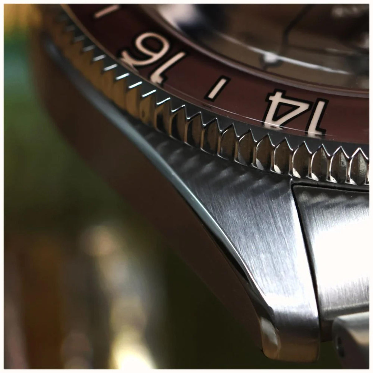 Close-up of steel watch bezel with lumed indices and numbered markings