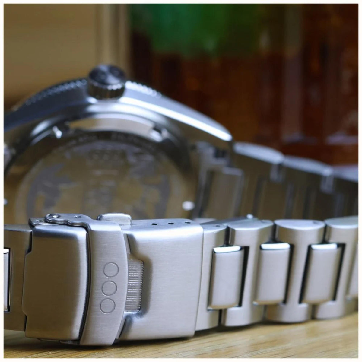 Steel watch bracelet and clasp detail with dark dial edge visible in side view