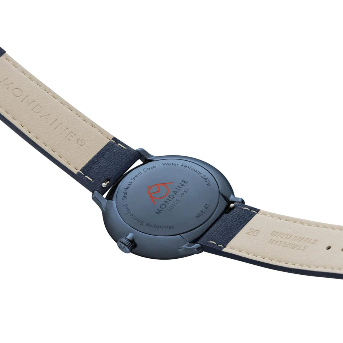 Close-up view of the blue caseback, showing engraved details reading 'Water Resistant 5ATM', 'Stainless Steel Case', and an orange Mondaine logo, flanked by the cream-colored interior linings of the strap