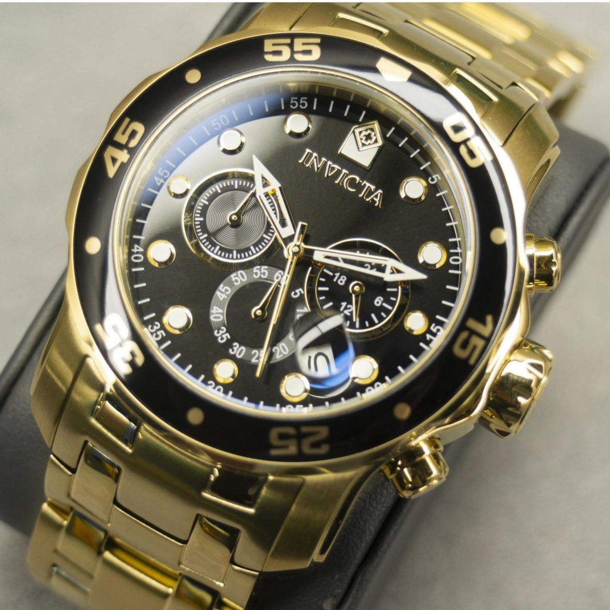 Invicta Pro Diver chronograph watch face close-up: black dial, gold indices and subdials.