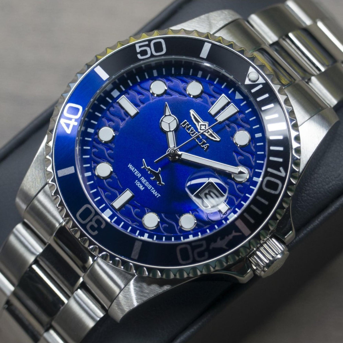 Blue dial dive watch close-up with steel bezel, lumed markers, date window