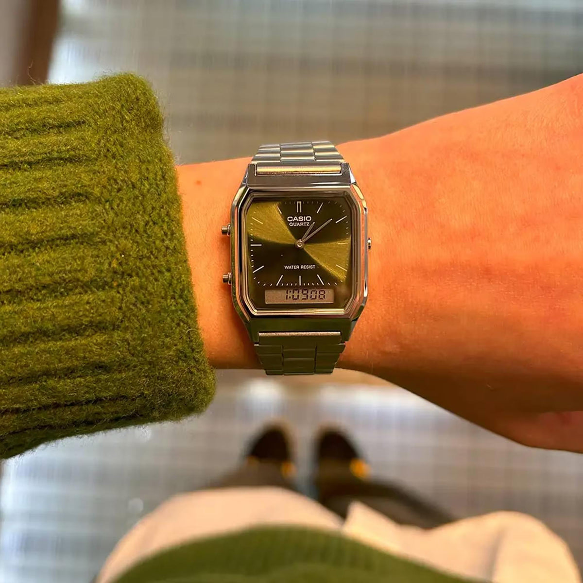 Green dial Casio quartz watch with stainless steel bracelet on wrist, front view