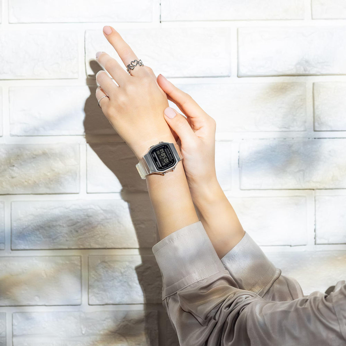 Close-up on a woman's wrist modeling the Casio Vintage Quartz Digital Resin Strap Watch A168XES-1BEF against a white brick wall background
