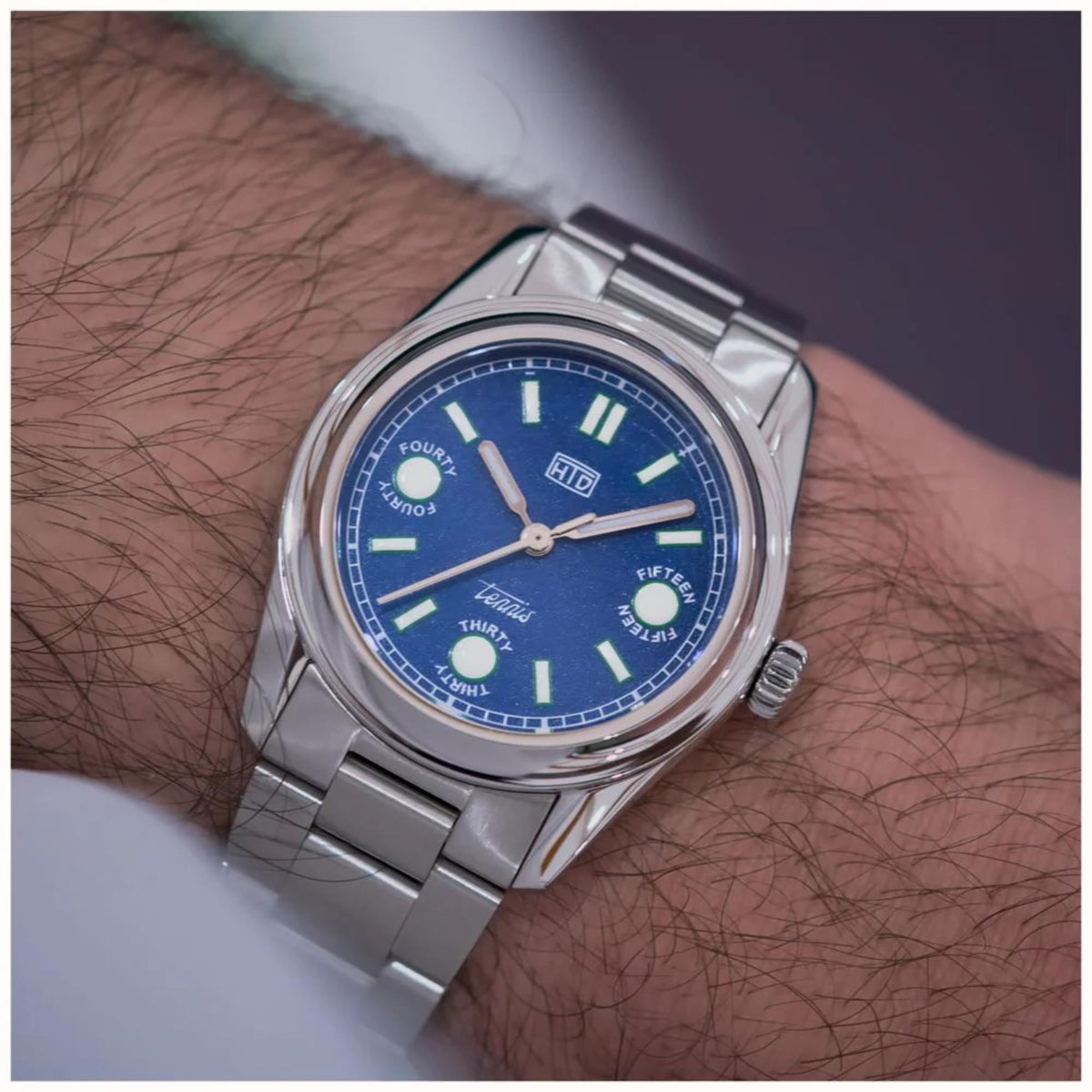 Stainless steel sports watch with light blue dial, round case, and metal bracelet