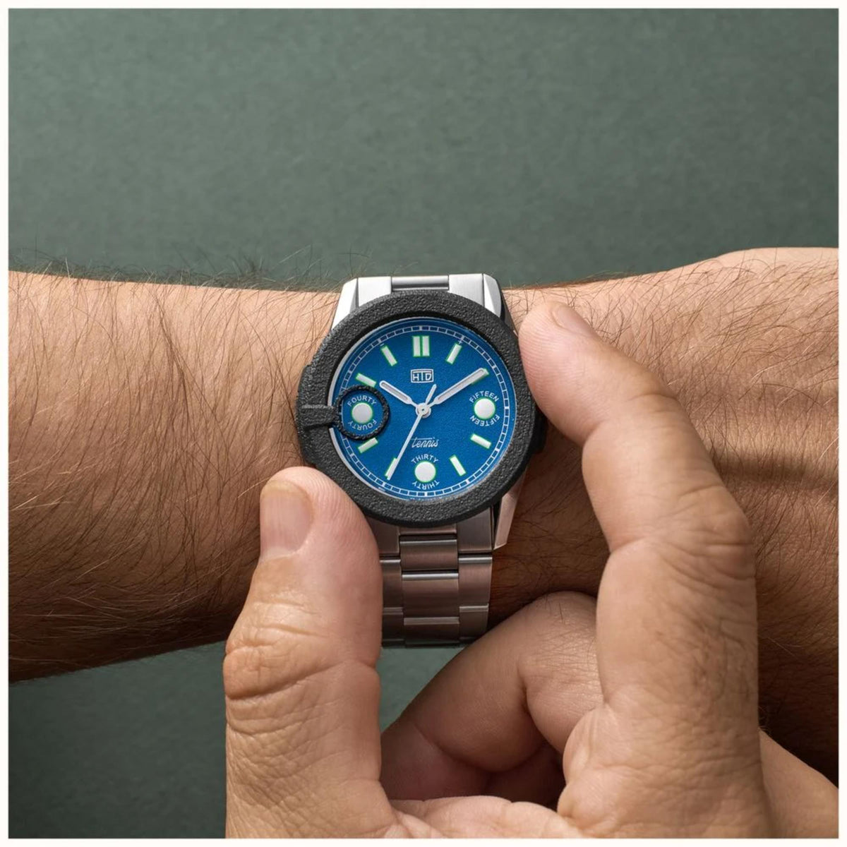 Stainless steel sports watch with light blue dial on wrist and linked metal bracelet
