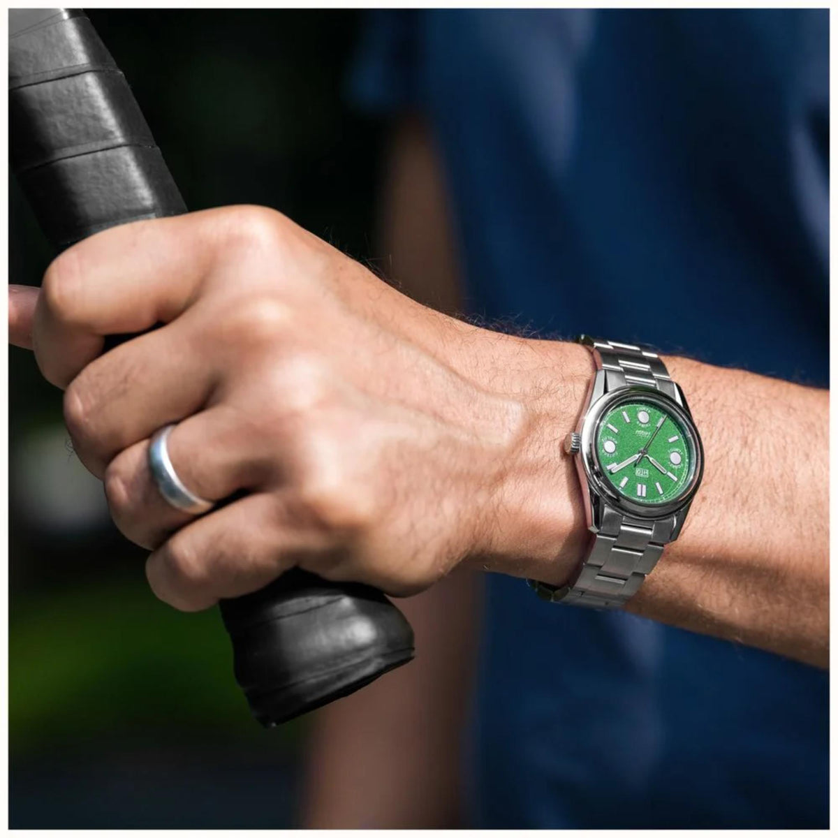 Automatic sports watch with green dial on steel bracelet, worn on wrist