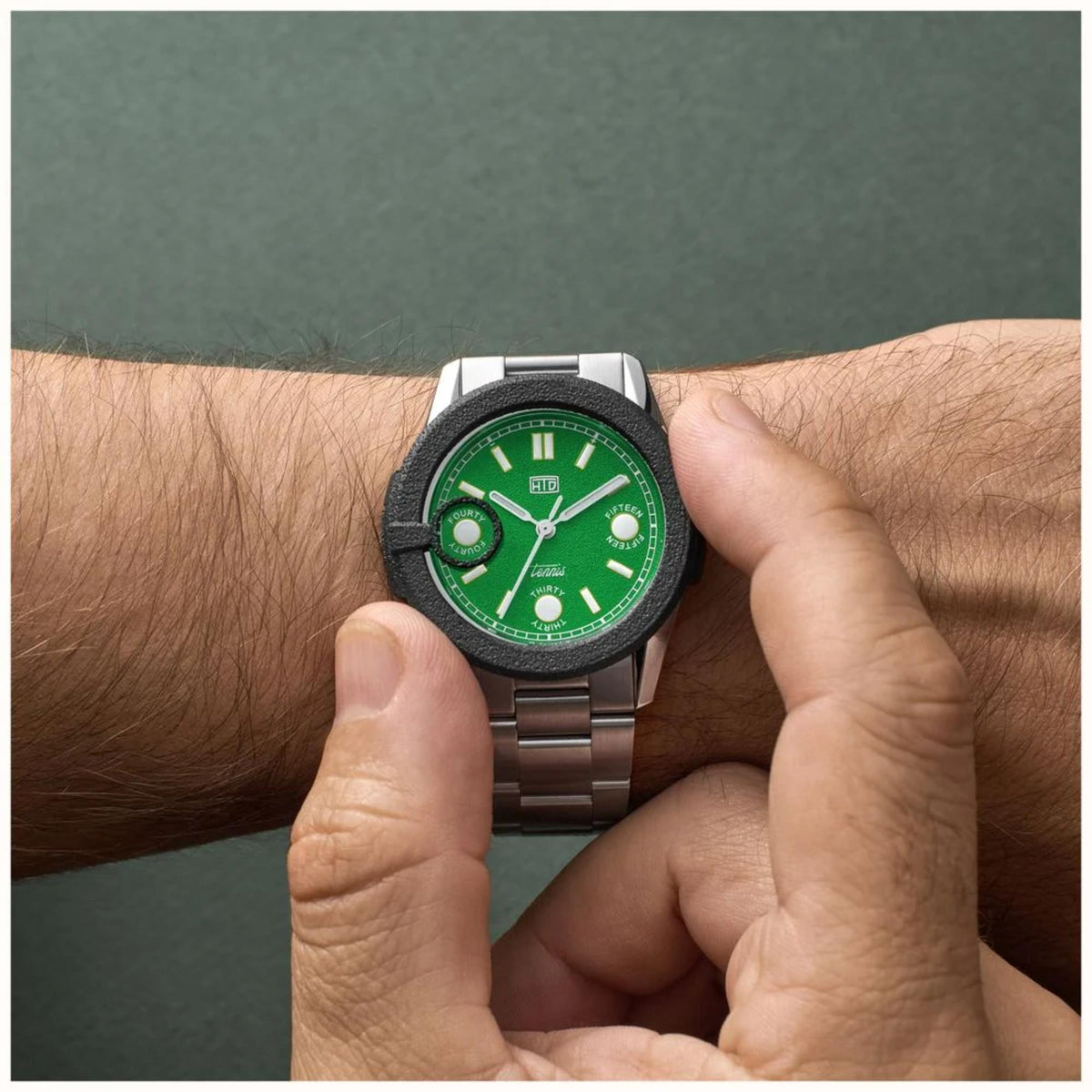 Automatic sports watch with green dial and steel bracelet, close-up on wrist