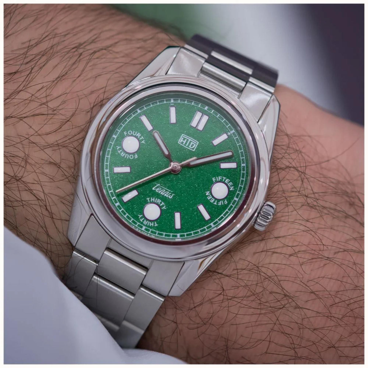 Automatic sports watch with green dial and steel bracelet, close side view on wrist