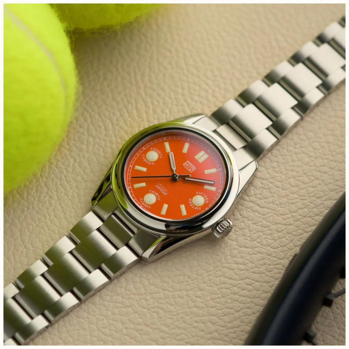 Orange dial steel sports watch with metal link bracelet and crown on side