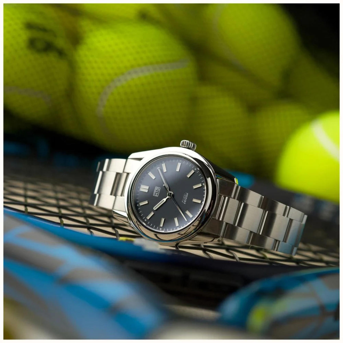 Blue dial stainless steel automatic sports watch on tennis court