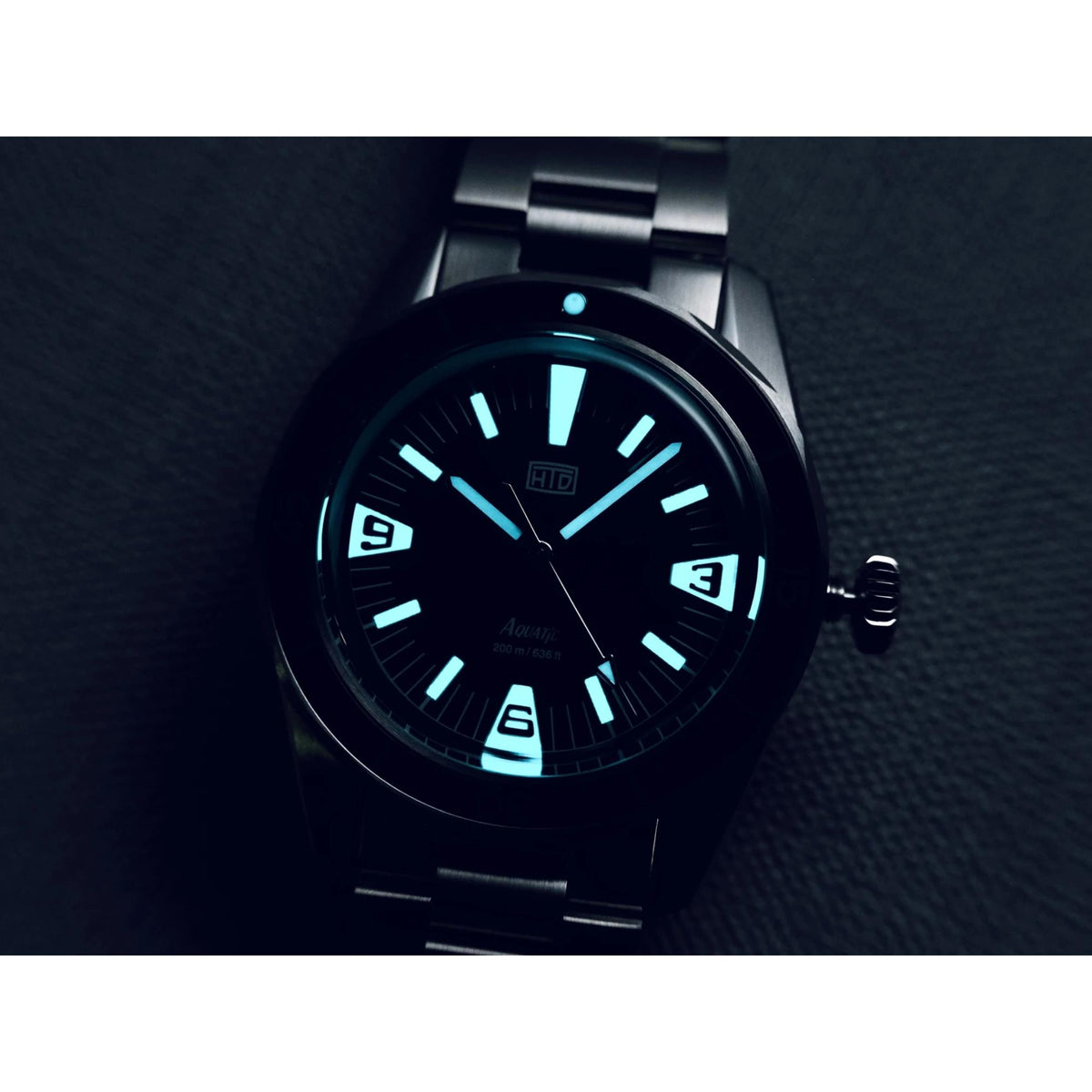 Close-up of black dial mens steel watch with glowing luminous hour markers