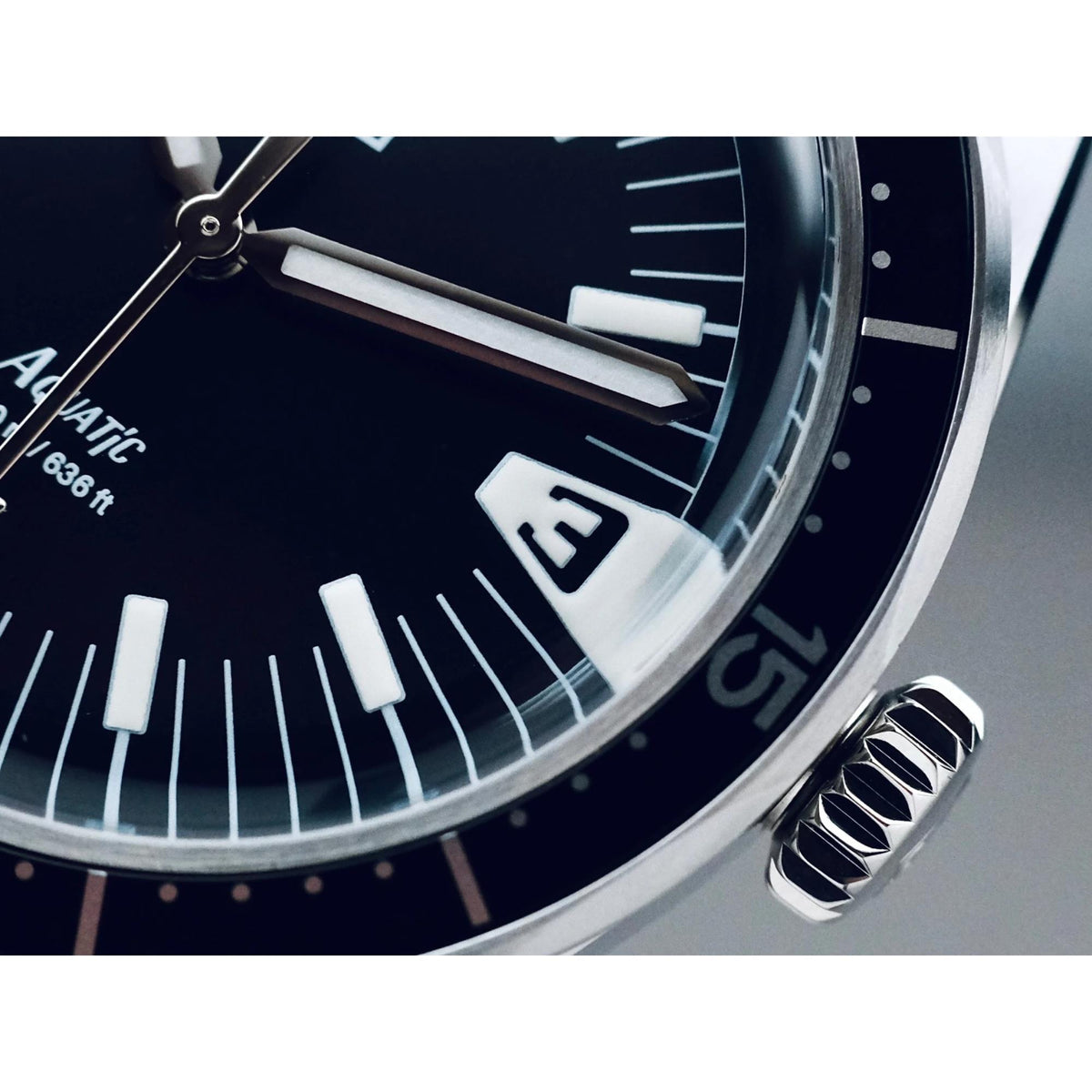 Close-up of black dial hands and luminous indices on steel diver watch