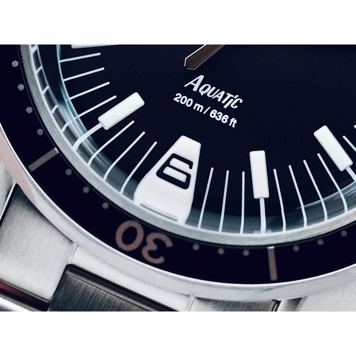 Close-up of black dial with white markers, Aquatic text, and 200 m depth scale