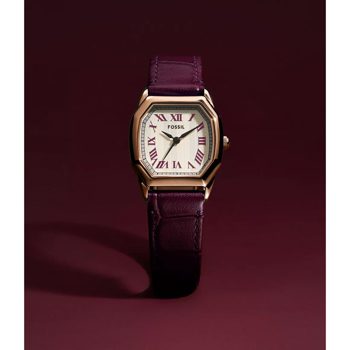 Close view of ladies quartz watch with rose gold case, white Roman numeral dial, dark purple strap