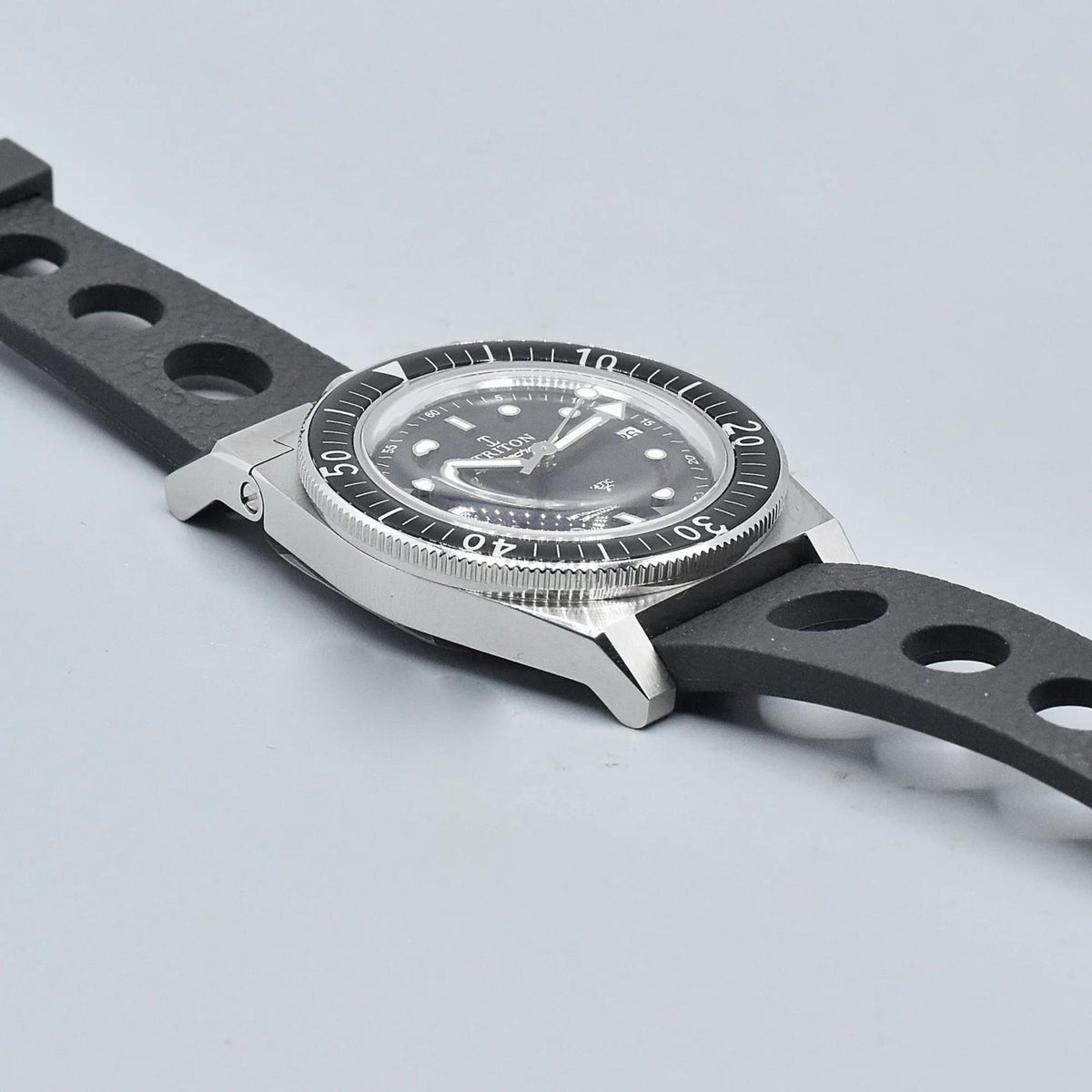 Men's dive watch top view, black dial and steel dive bezel, black rubber strap.