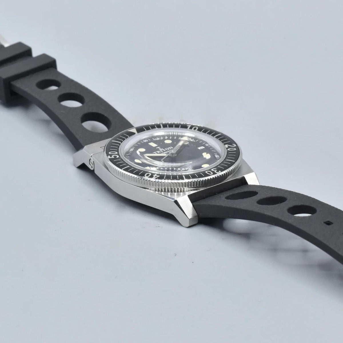 Men's black dial dive watch on black rubber strap with circular cutouts