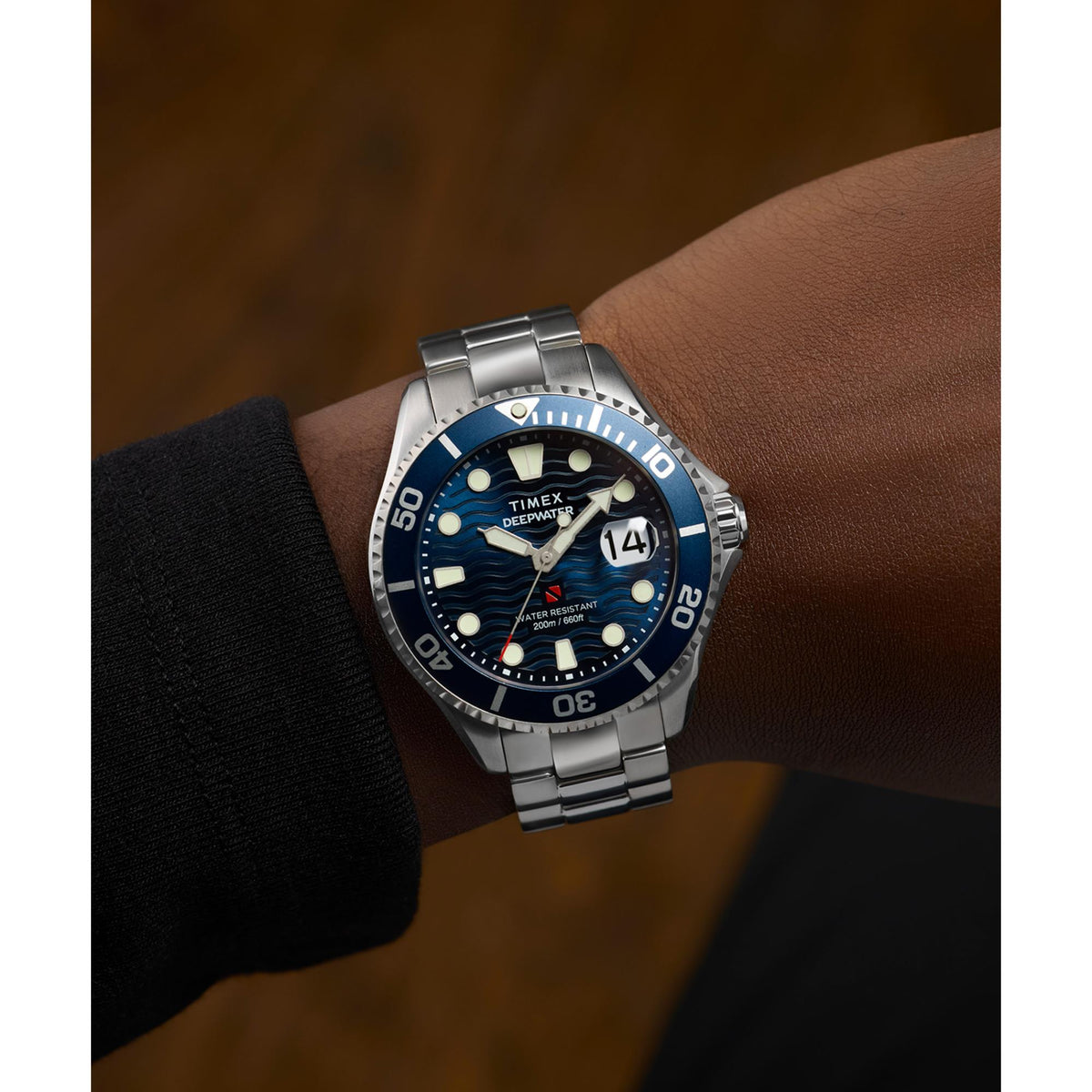 Men's steel dive watch with blue dial on wrist, dark bezel, metal bracelet