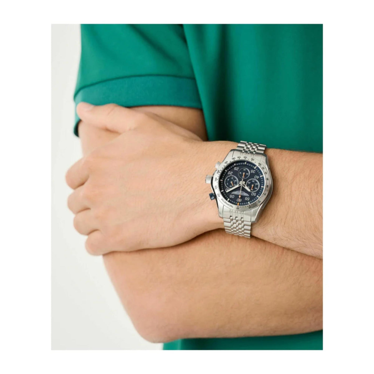 Aston Martin chronograph watch worn on wrist with blue dial and steel bracelet.