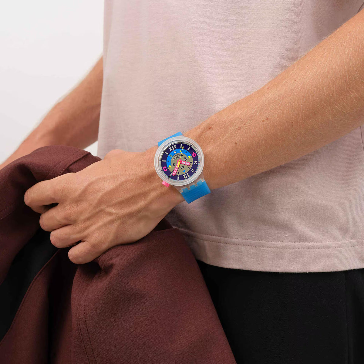 Blue silicone strap watch on wrist over light shirt, colorful dark blue dial