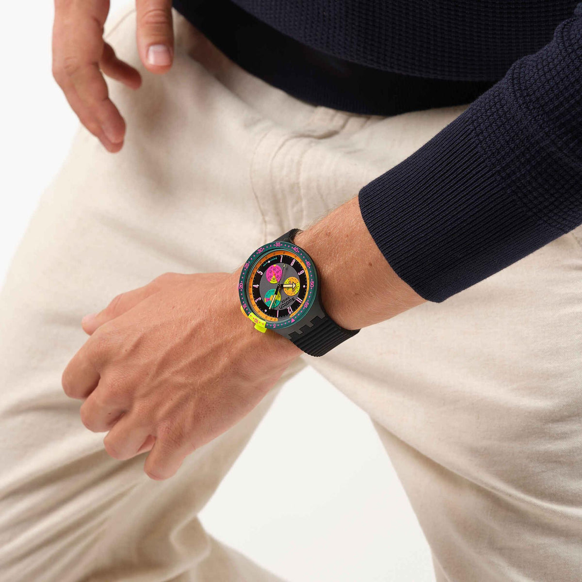 Neon bezel chronograph watch worn on wrist with black silicone strap