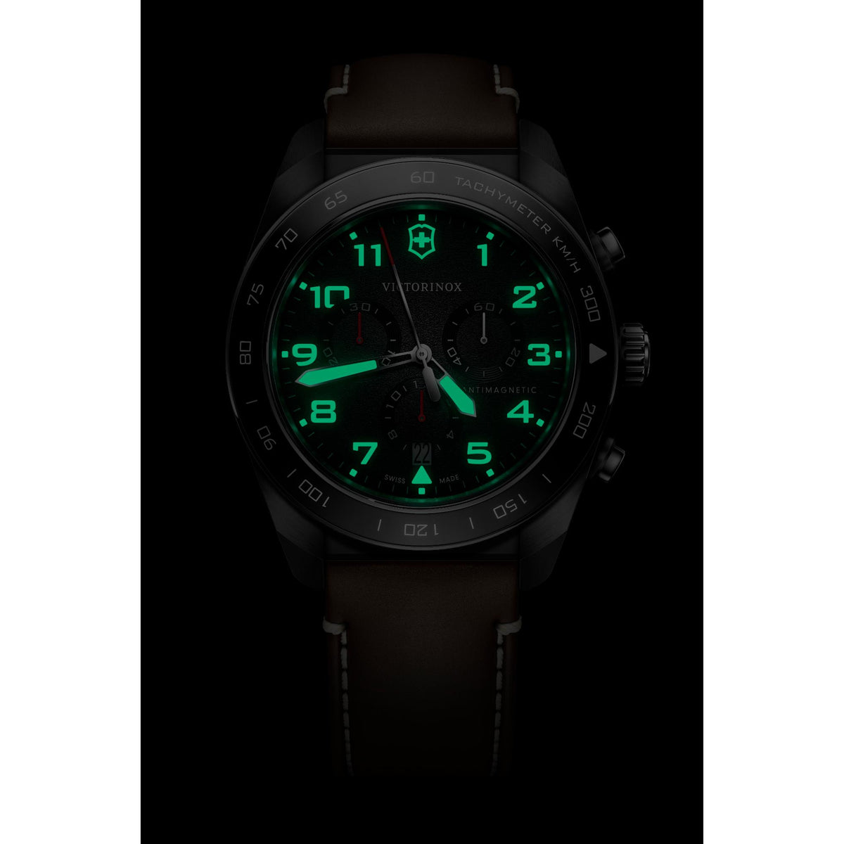 Victorinox Swiss Army 242046 chronograph watch with glowing green lume hands and markers on black dial in dark setting