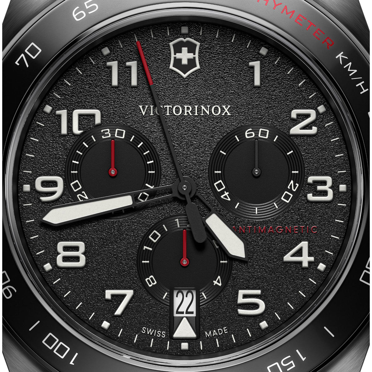 Close-up chronograph dial, black textured face with large numbers, subdials, red accents