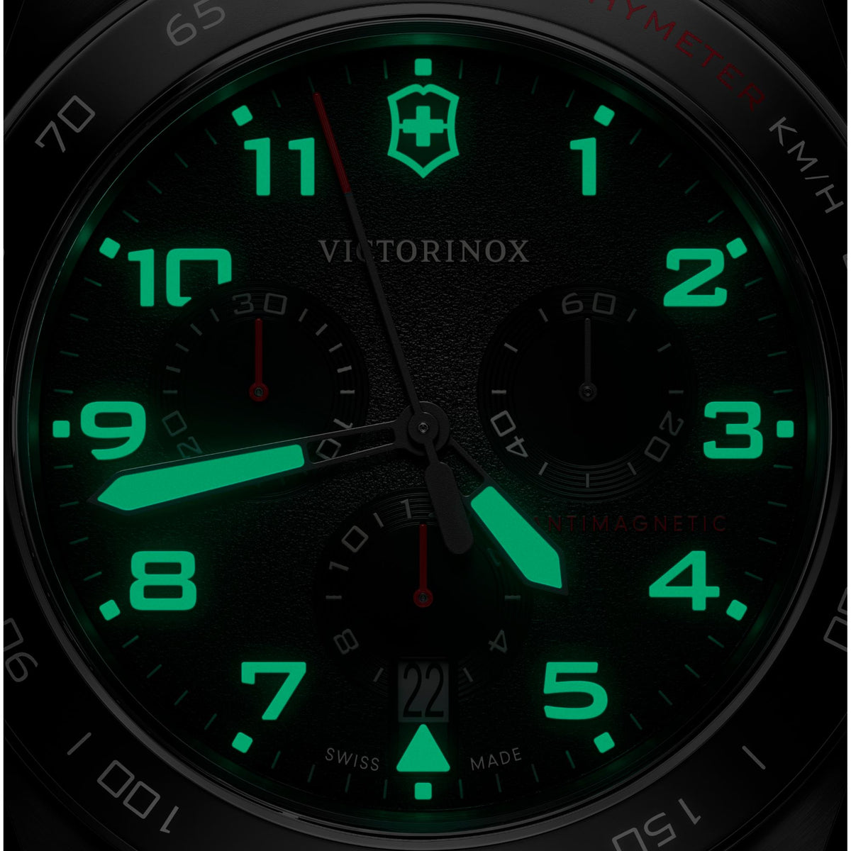 Close-up black dial with bright green numerals and markers, subdials, chronograph