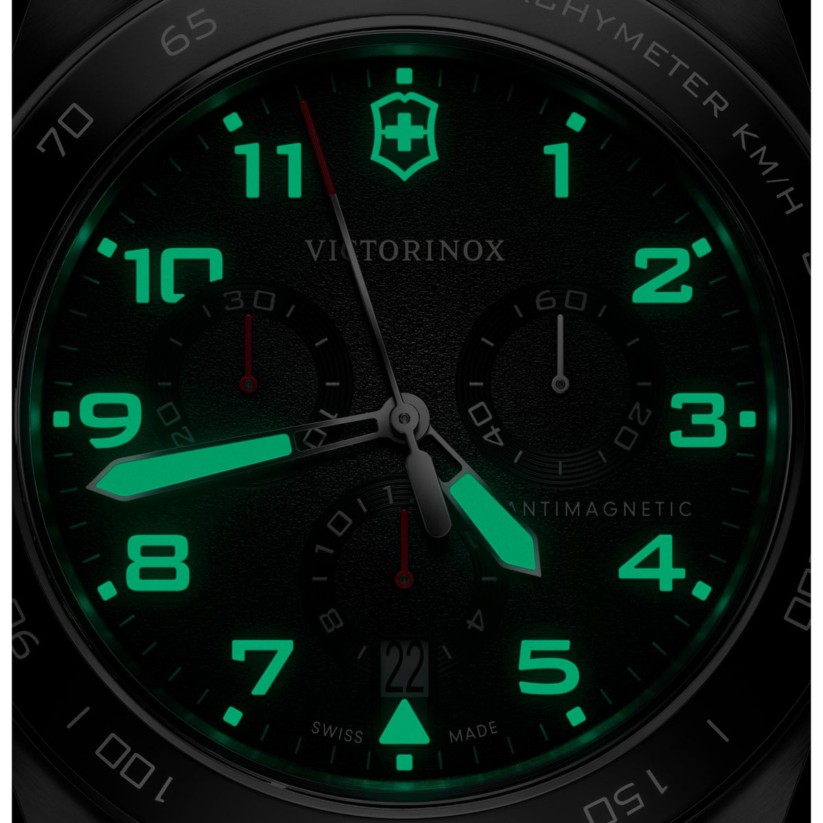 Luminous green chronograph dial close-up with three subdials and red-tipped hands