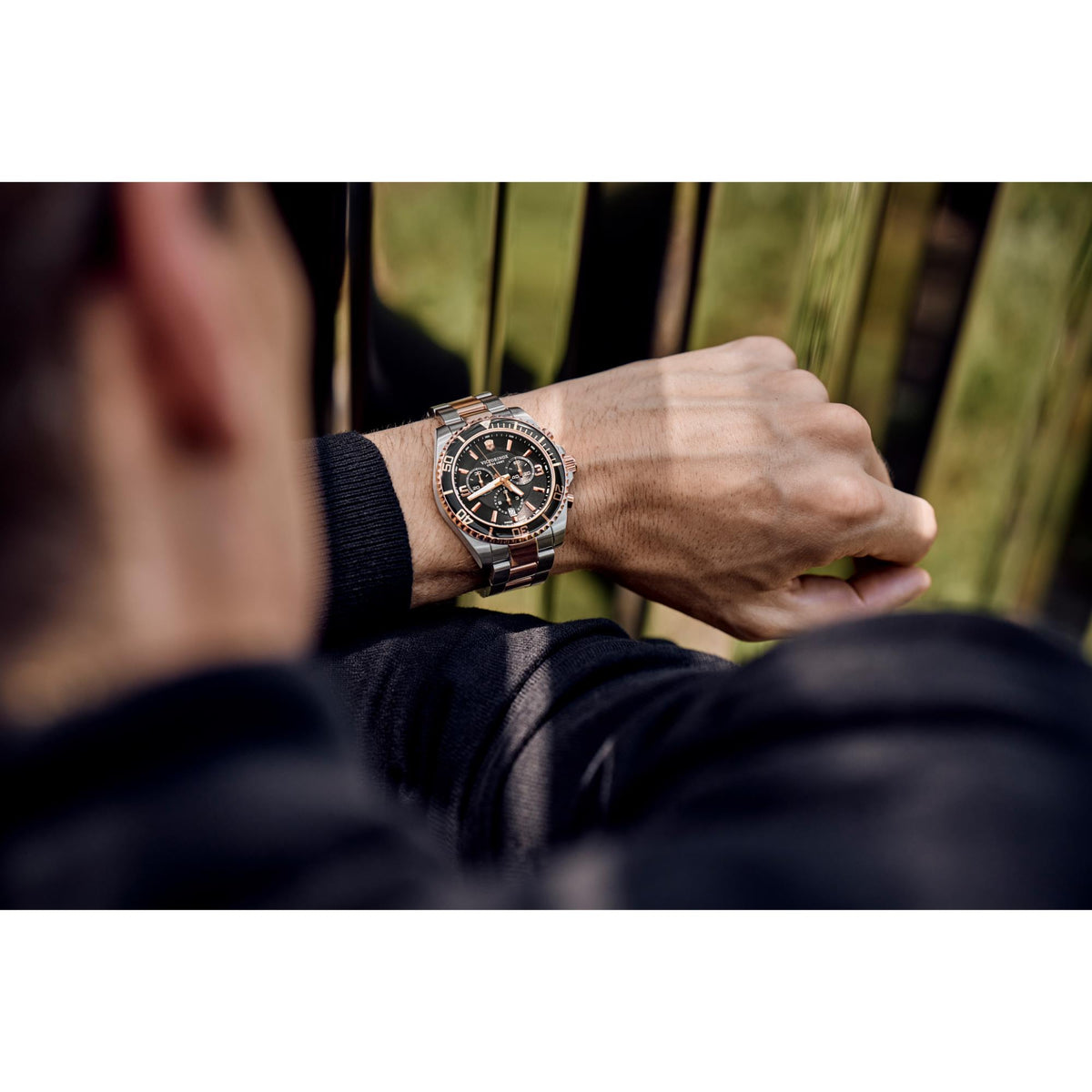 Men's chronograph watch on wrist, black dial with rose-gold accents and steel bracelet