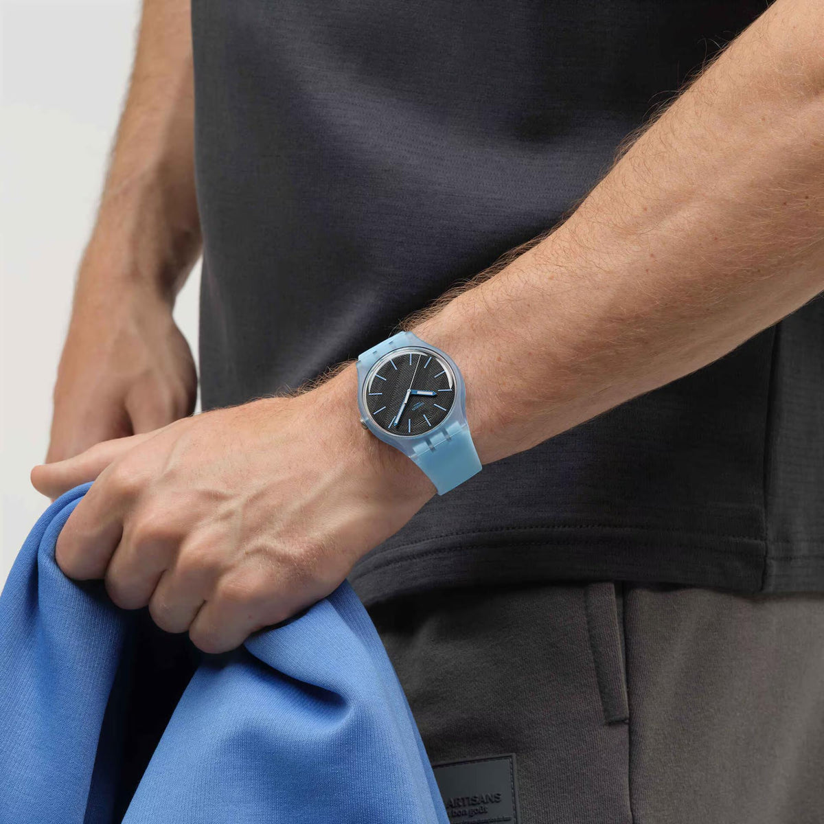 Quartz watch on wrist with light blue silicone strap and black dial