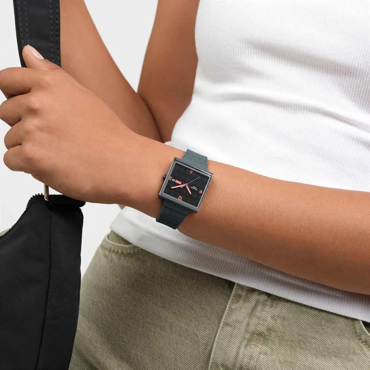 Black square dial quartz watch with red hands, dark silicone strap on wrist