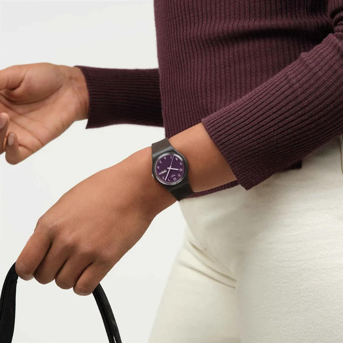Purple-dial wristwatch with dark silicone strap on a wrist