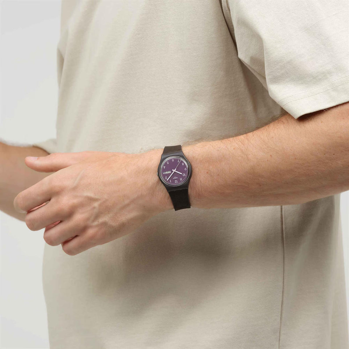 Purple dial wristwatch with dark silicone strap, close-up on wrist