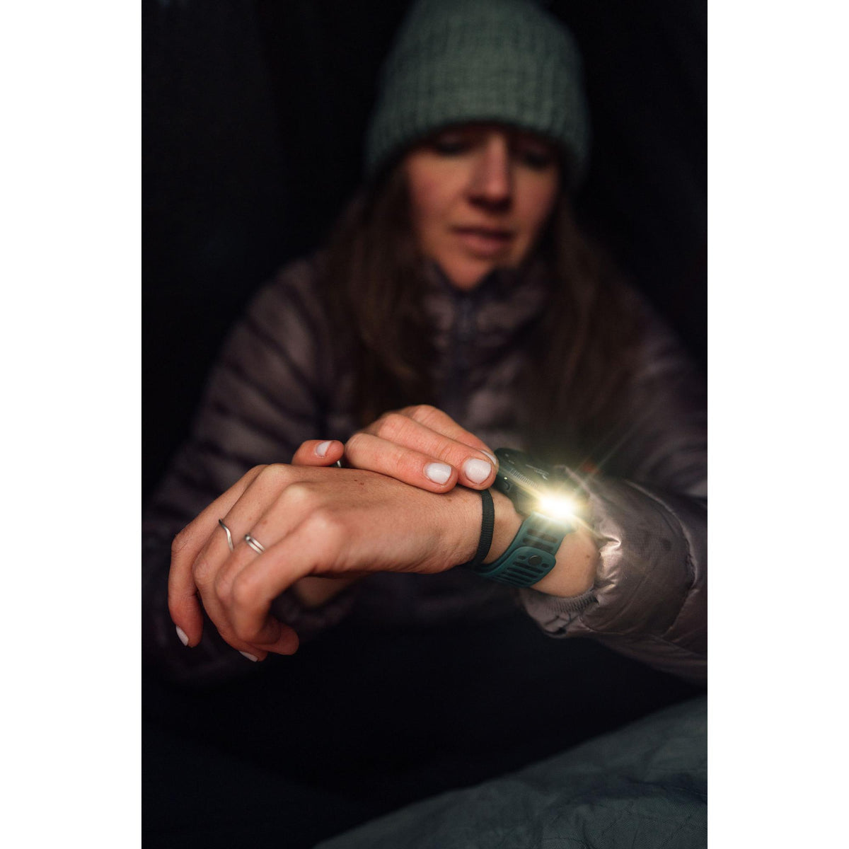 Suunto Vertical 2 Canyon SS051206000 AMOLED Digital Silicone Strap Smart Watch worn on the wrist utilizing built-in LED flashlight in a dark environment
