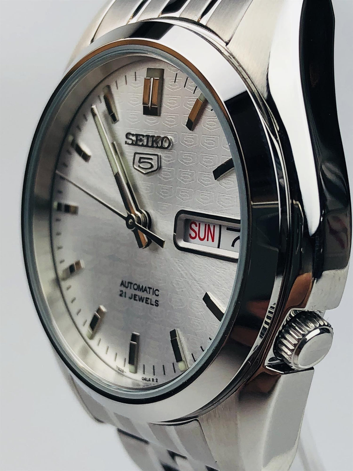 Angled profile view of the Seiko 5 SNK355K1 watch showcasing its polished stainless steel case and recessed 4 o'clock crown