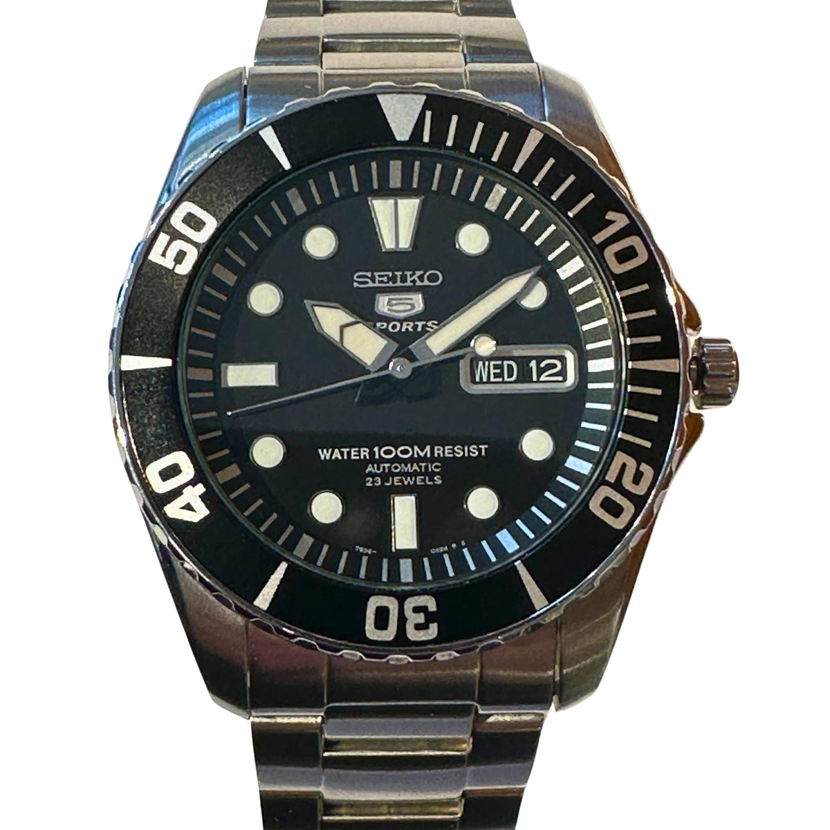 Men’s stainless steel watch with black dial, diver bezel, and bracelet, date showing Wed 12