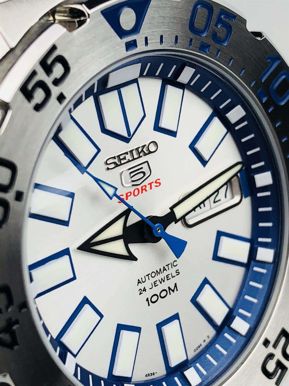White dial men’s watch with blue markers, skeleton hands, and date display
