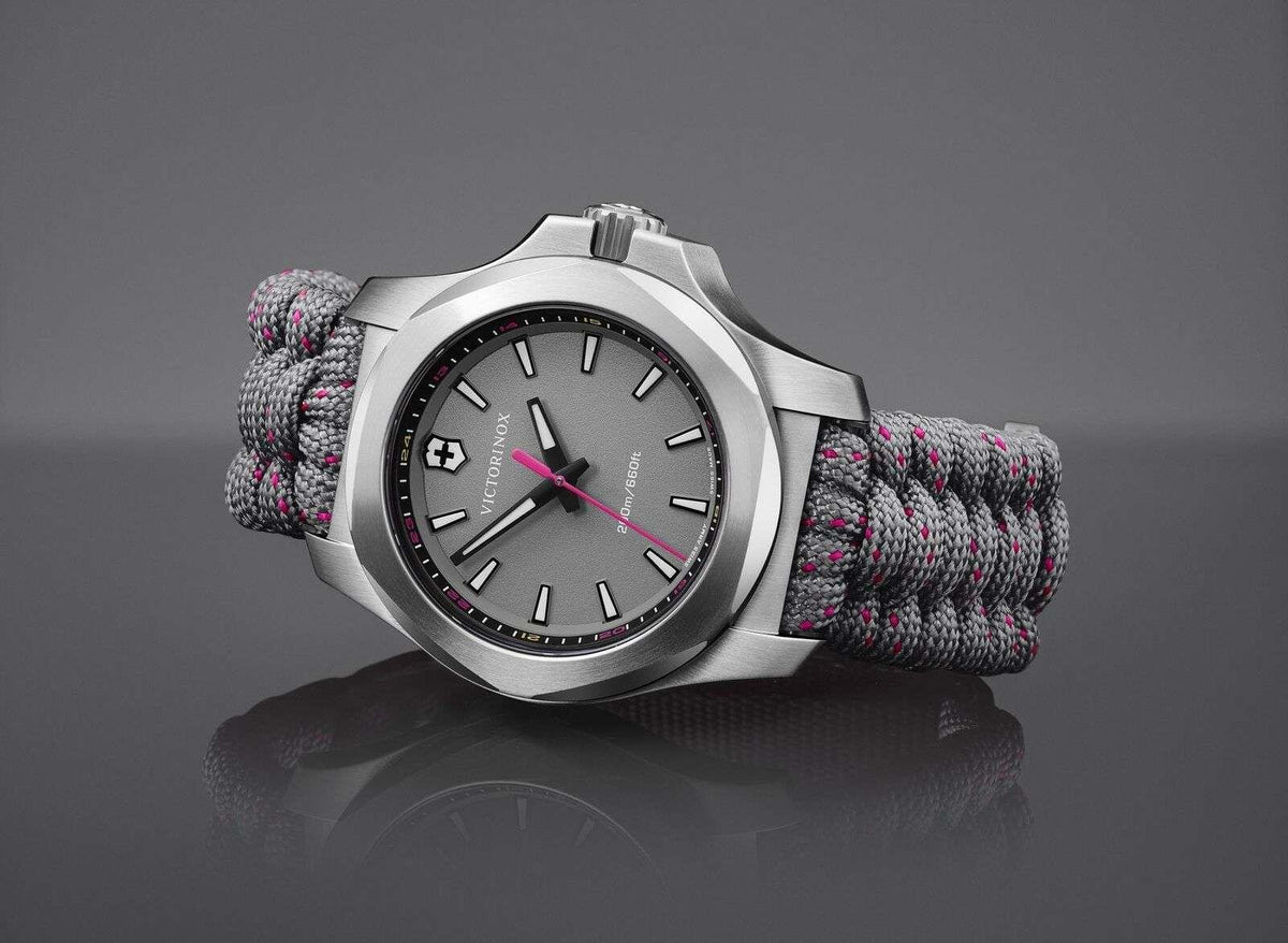 Silver stainless steel quartz watch with dark dial, gray paracord strap and pink accents