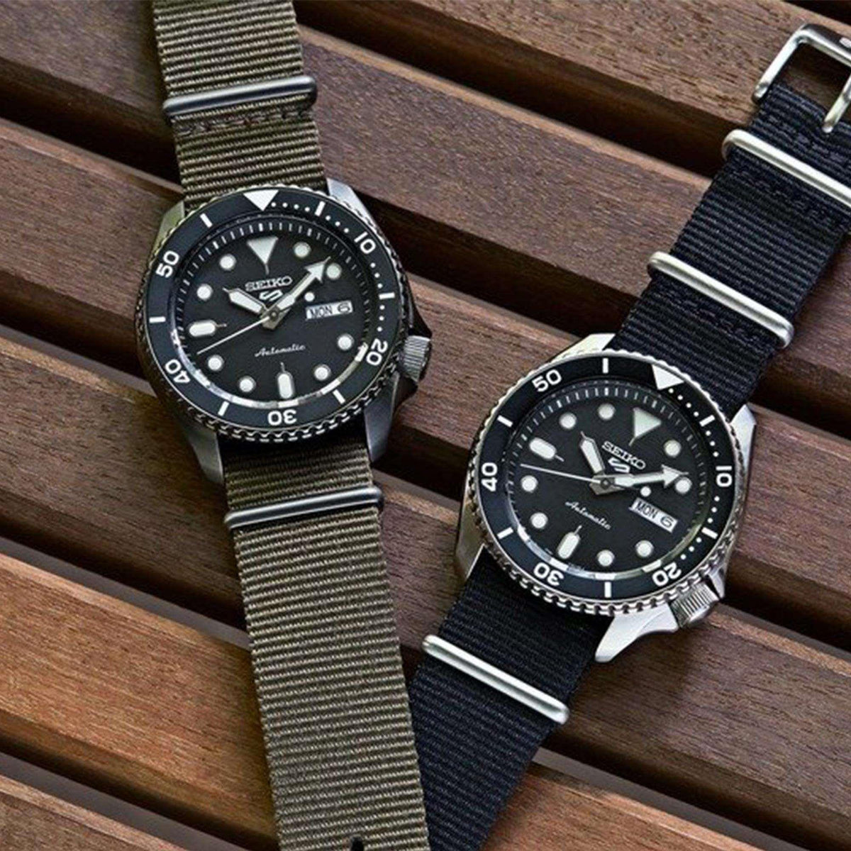Two Seiko automatic dive watches with black dials and black/green fabric straps.