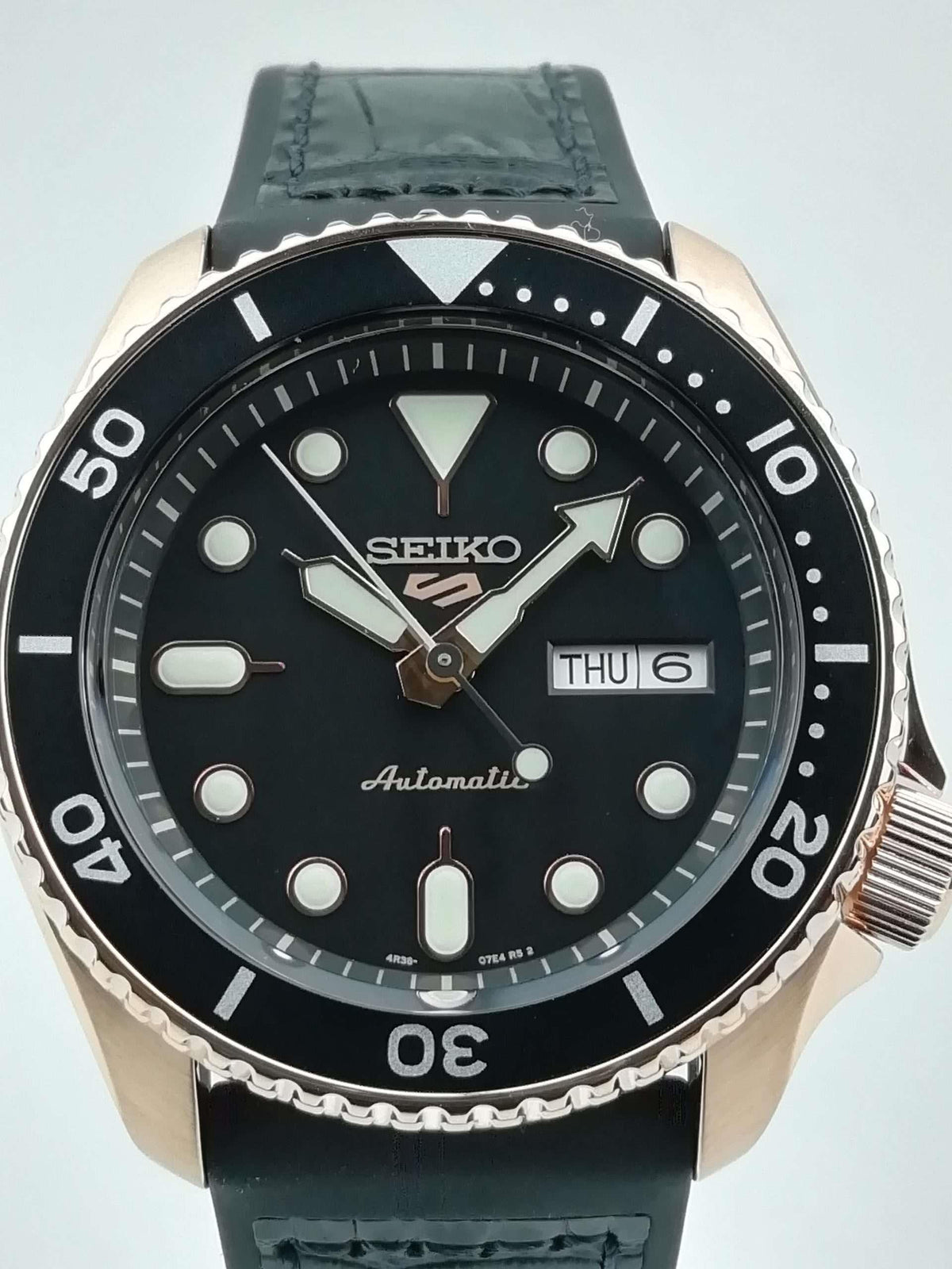 Men's Seiko 5 Sports automatic watch front view, black dial with THU 6 window and black strap