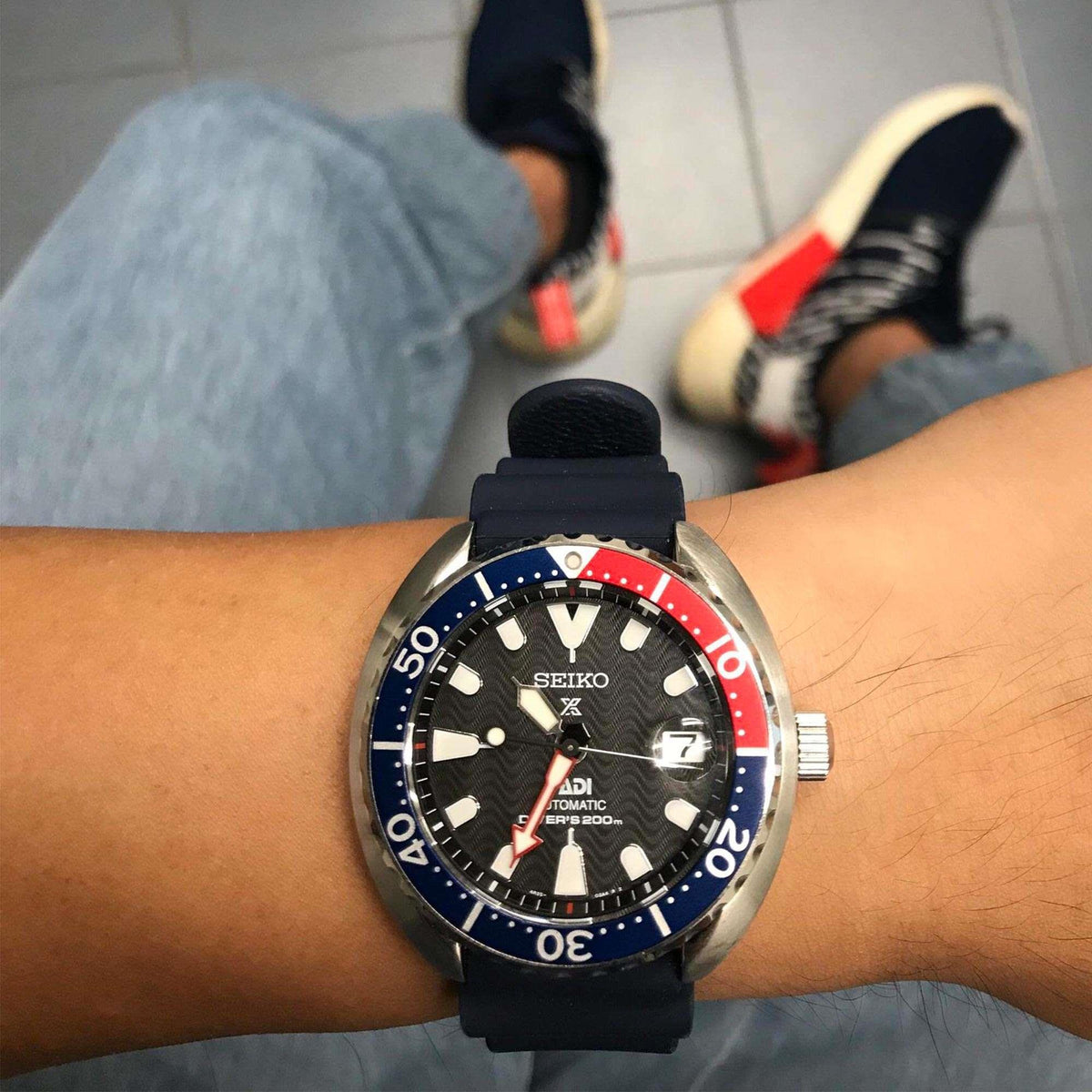 Men's dive watch on wrist, black dial, Pepsi blue/red bezel, navy silicone band