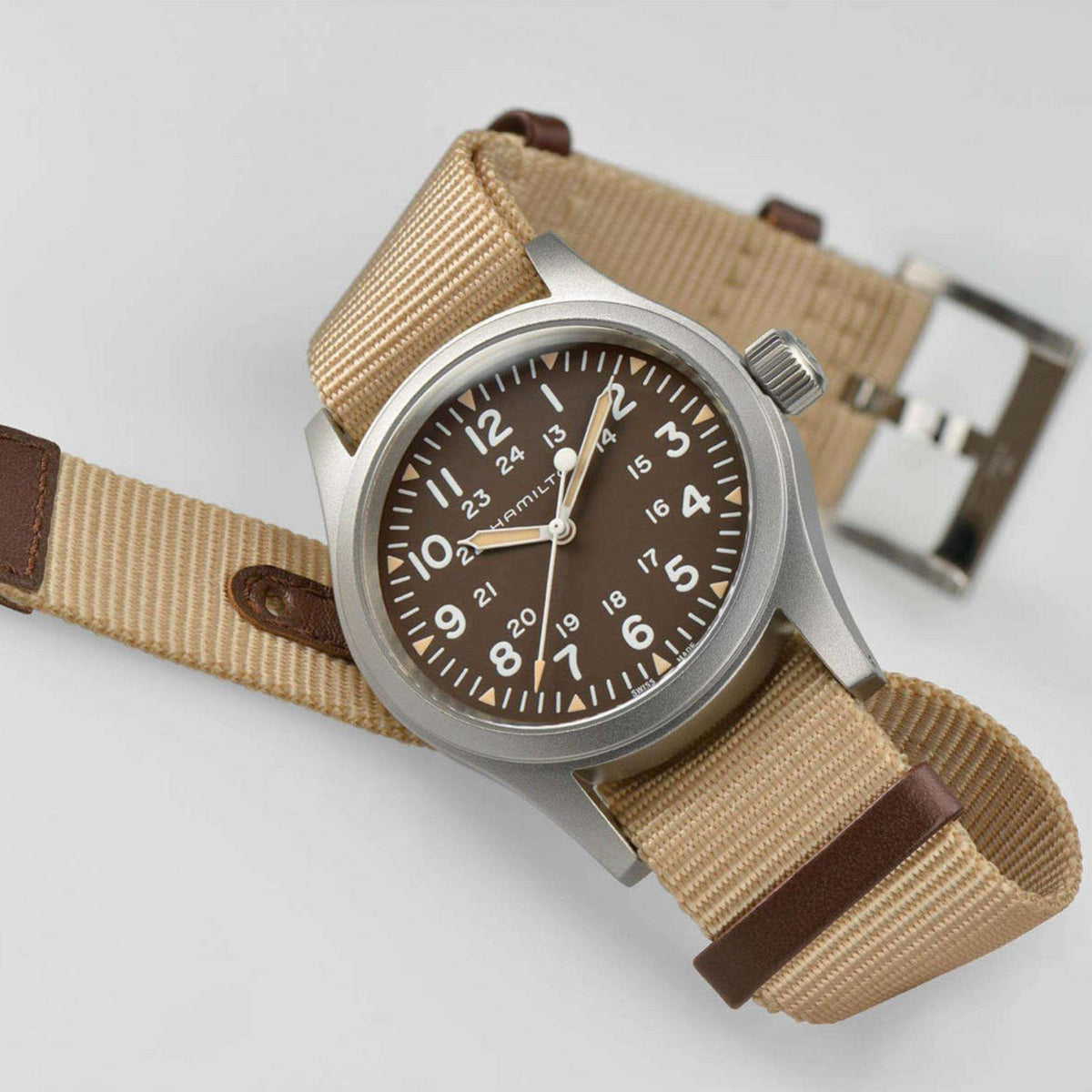 Men’s mechanical field watch angled 3/4 view, dark brown dial, tan NATO strap with brown trim.